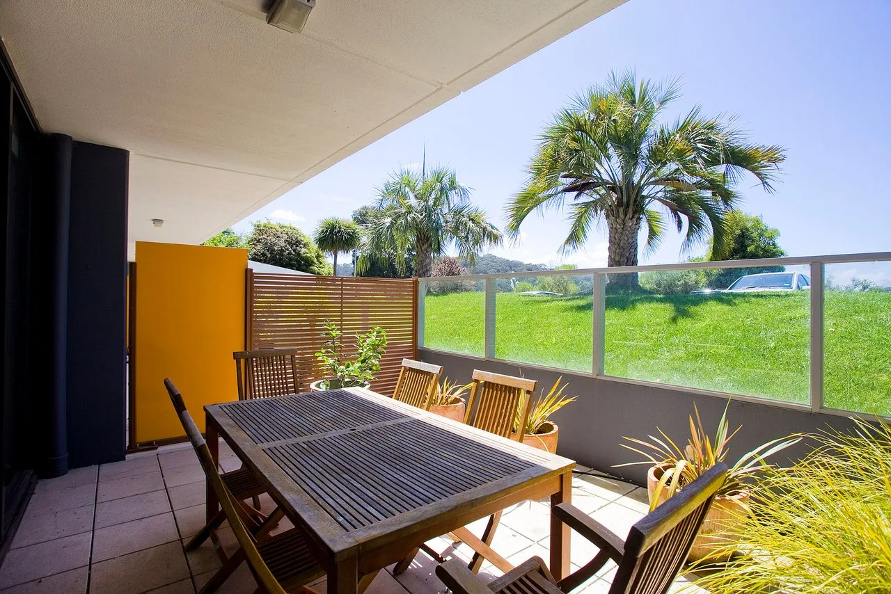 Un patio exterior con mesa y sillas da a una zona de césped.