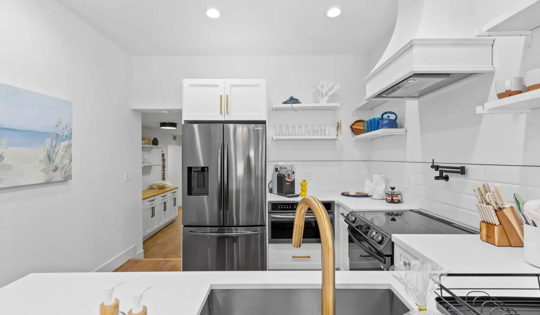 Una cocina luminosa con electrodomésticos de acero inoxidable y gabinetes blancos.