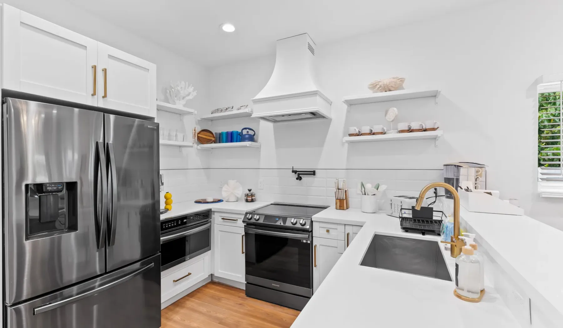Una cocina blanca y luminosa con electrodomésticos de acero inoxidable e isla central.