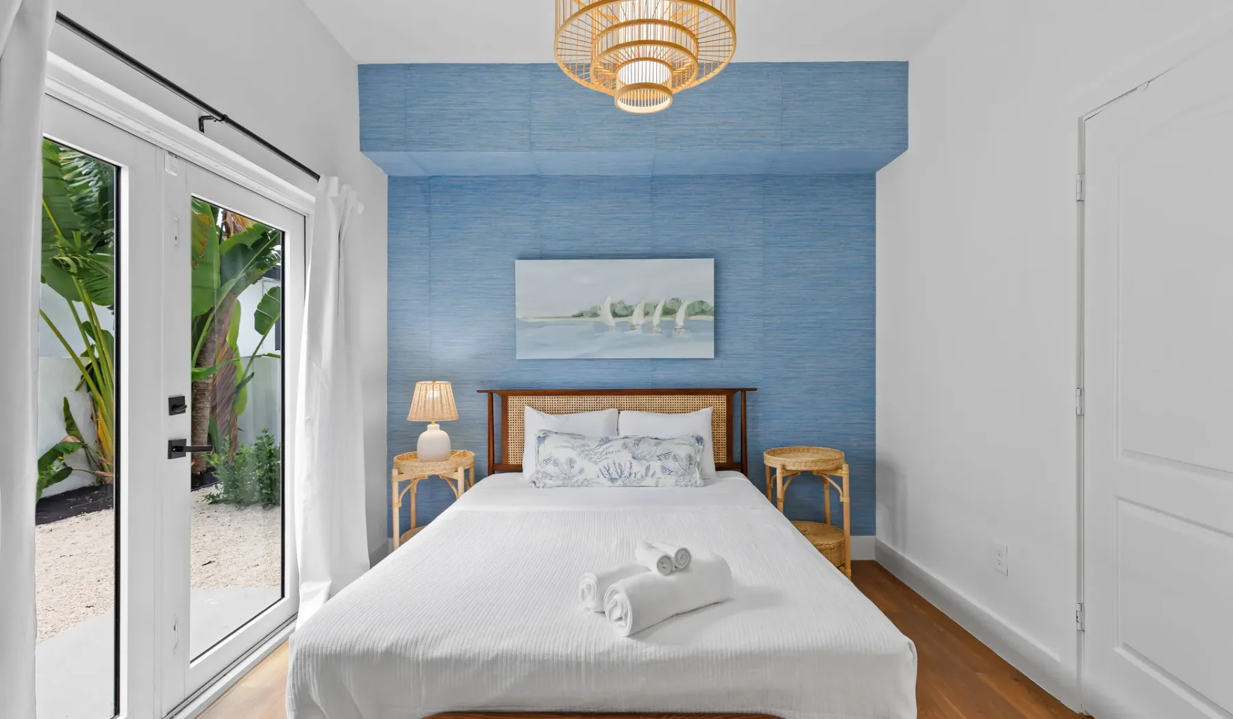 Un dormitorio con una cama frente a una pared azul y puertas de vidrio.