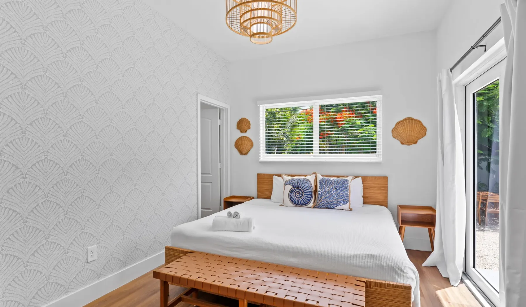 Un dormitorio luminoso con una cama bien tendida y una ventana grande.