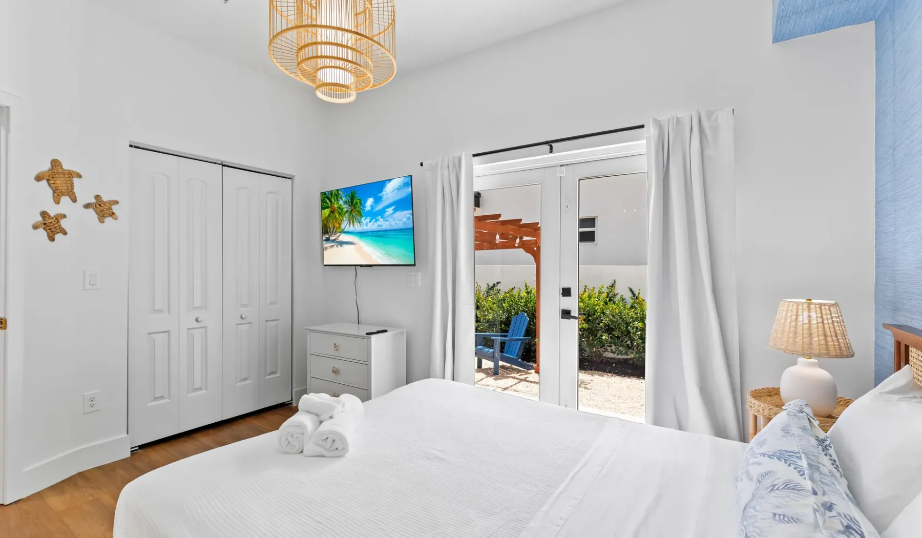 Un dormitorio luminoso con una cama tendida y puertas de vidrio que dan a un patio.