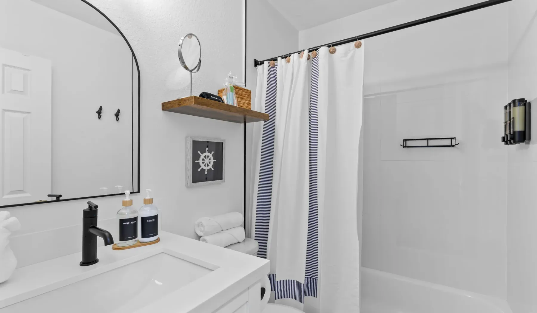 Un baño luminoso con lavabo, espejo grande y cortina de ducha.