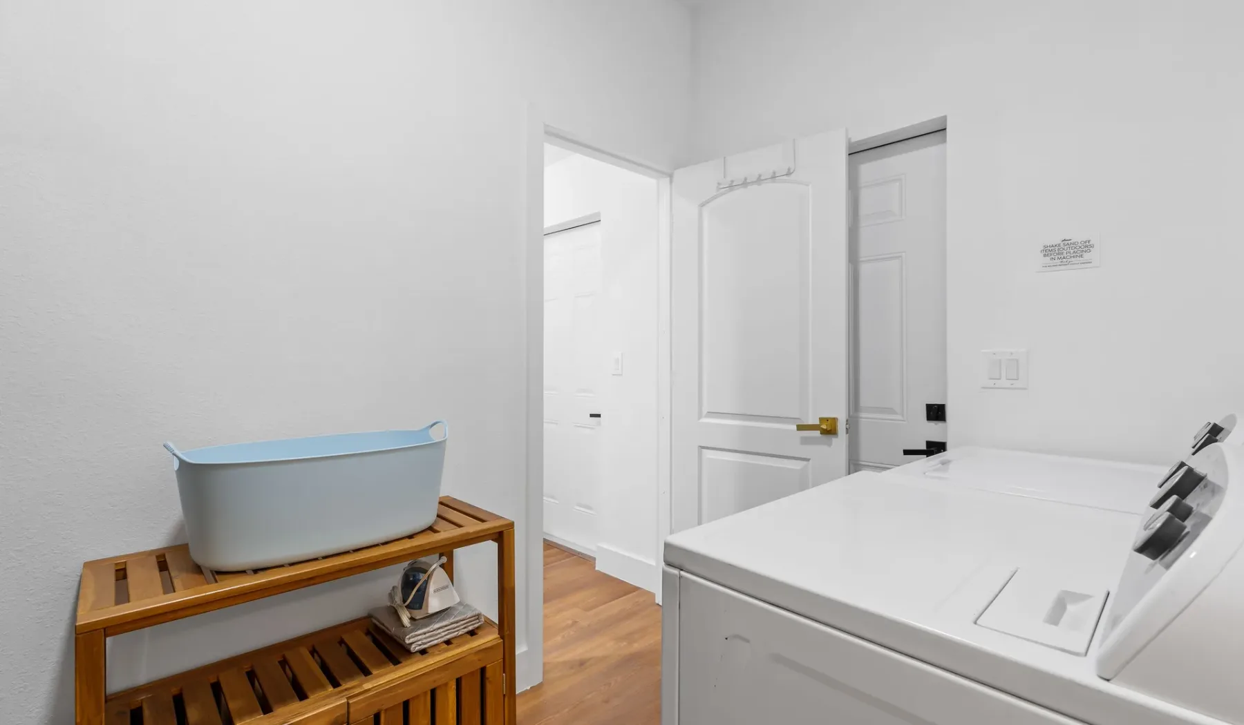Un cuarto de lavado con una lavadora y un estante de madera.