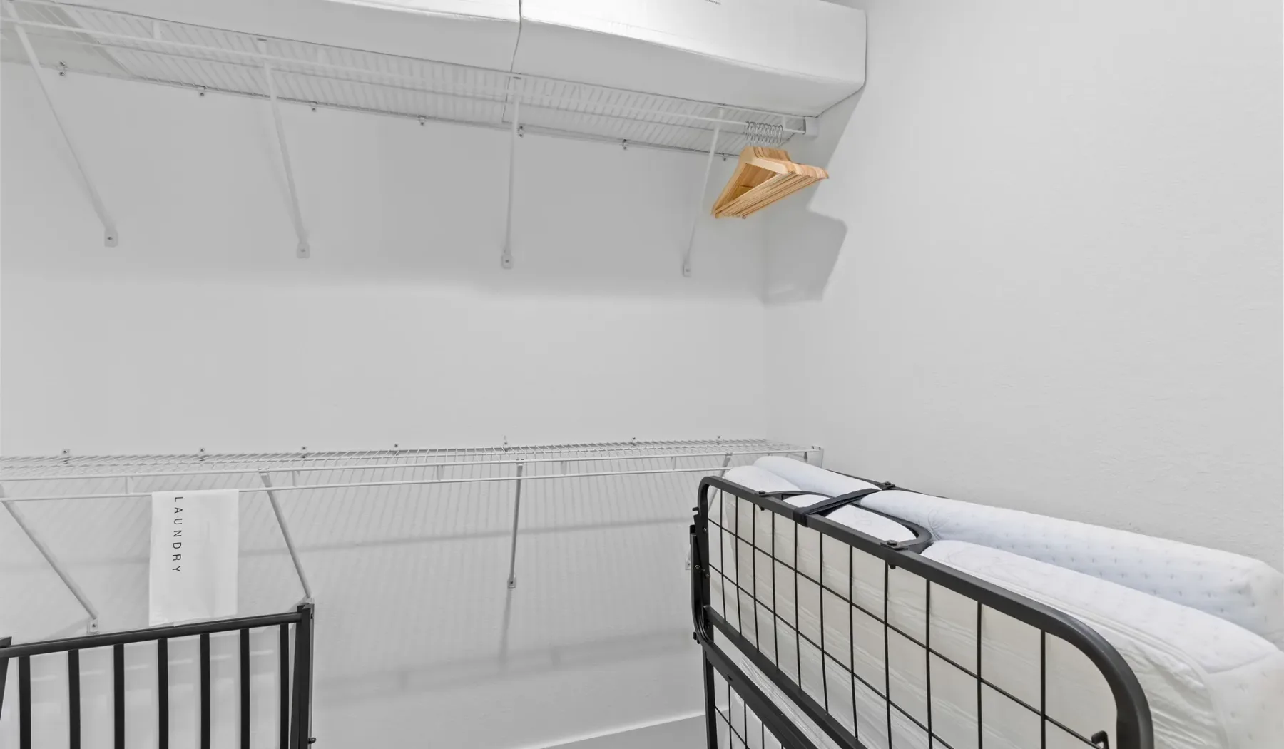 Una zona para dormir blanca con literas de metal negro y estantes de alambre.