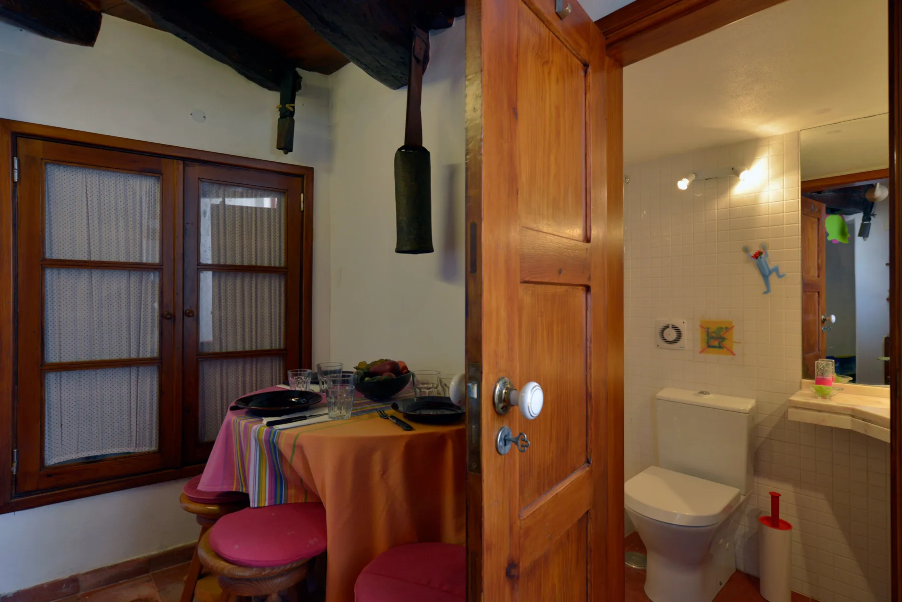 Un comedor con una mesa junto a una puerta abierta que da a un baño.