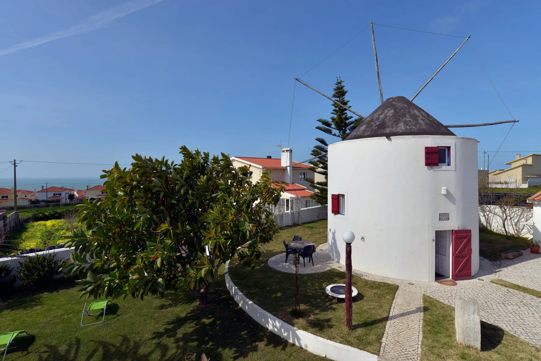 Un molino blanco se encuentra junto a un jardín y un sendero pavimentado.