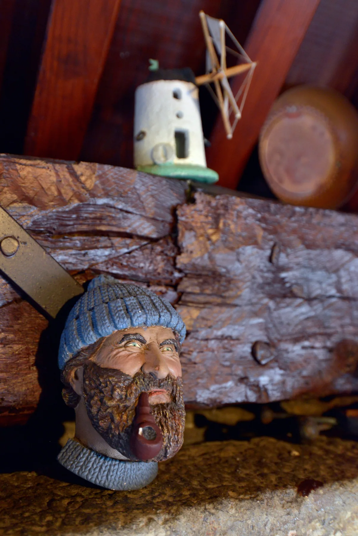 Una decoración rústica muestra una figura tallada con barba bajo un pequeño adorno de faro.