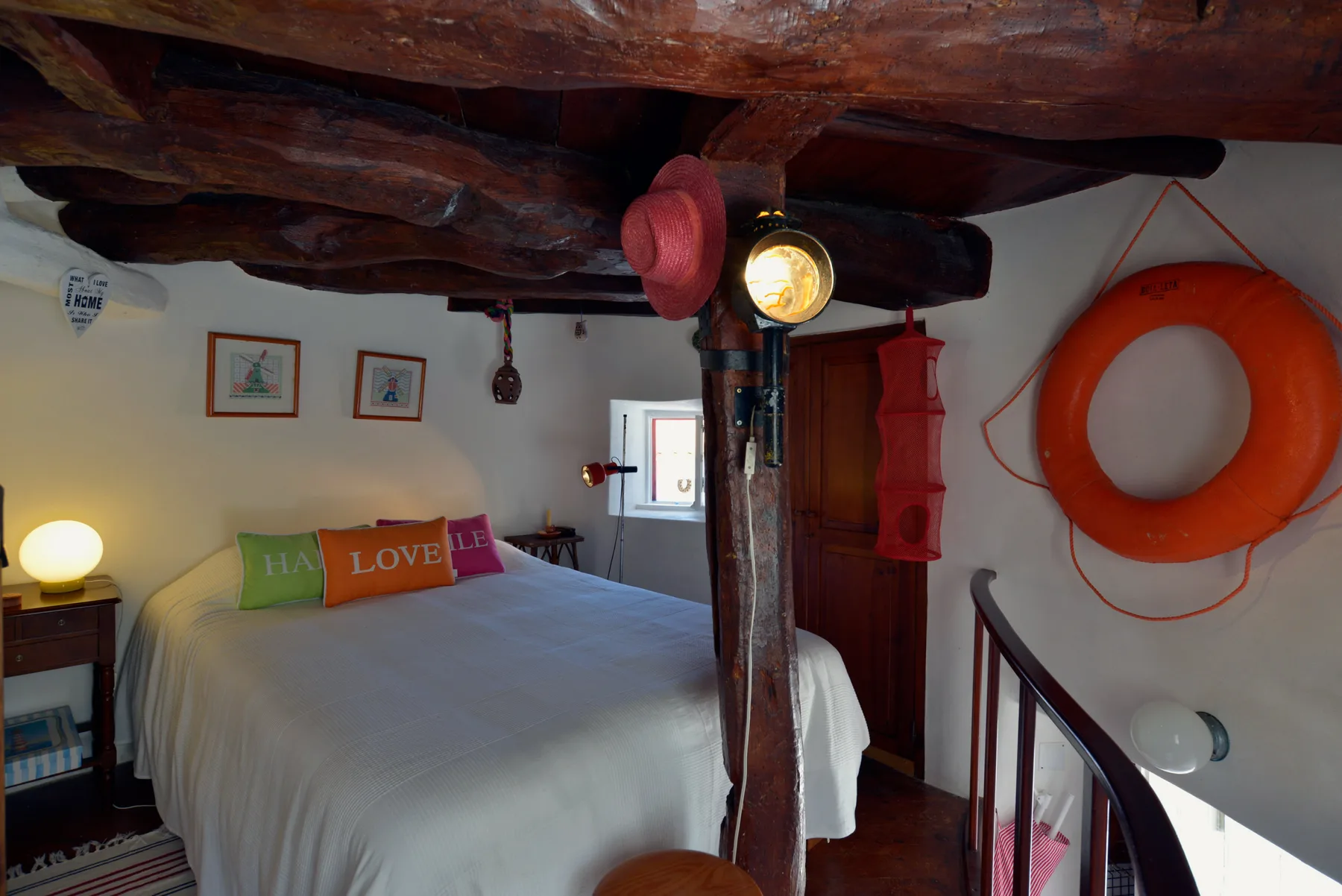 Un dormitorio con una cama bajo vigas oscuras a la vista y un flotador naranja en la pared.