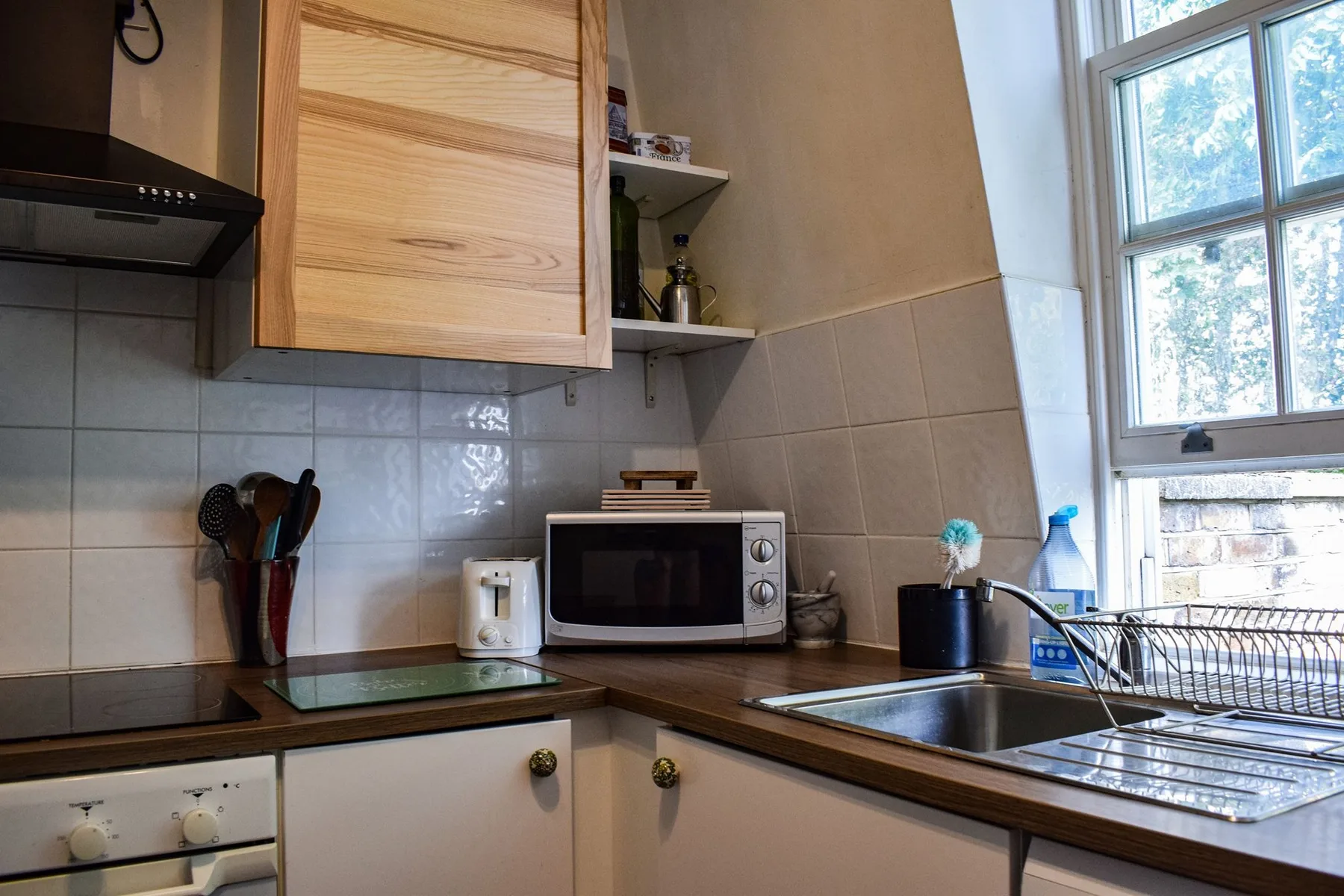 Una cocina con microondas, fregadero y una ventana grande.