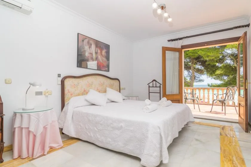 Un dormitorio luminoso con una cama y puertas abiertas que dan a un balcón.