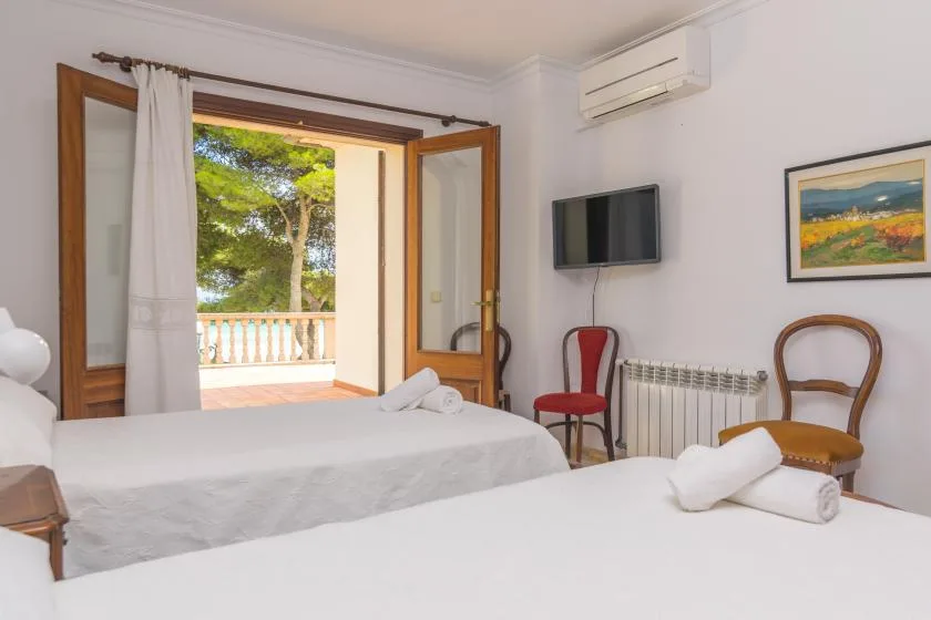 Un dormitorio con dos camas y puertas abiertas que dan a un balcón.