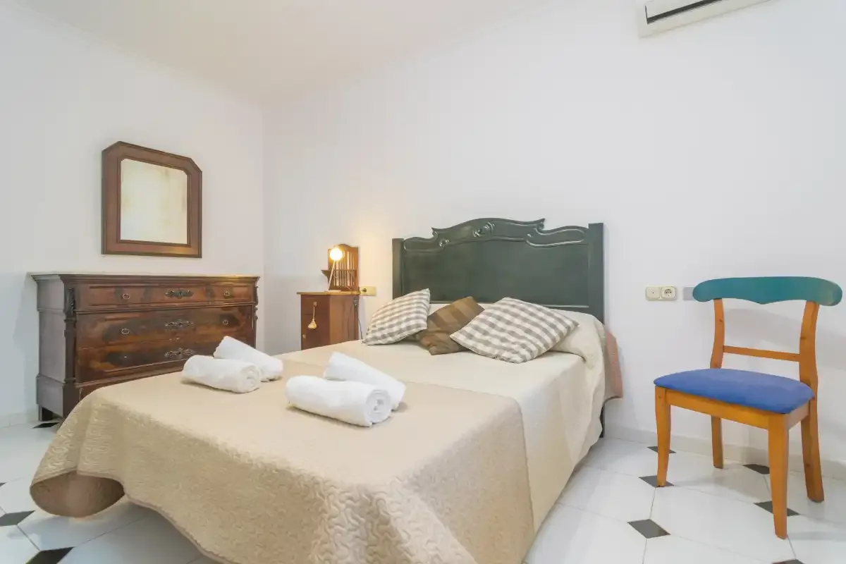 Un dormitorio con una cama doble, toallas dobladas y muebles de madera.