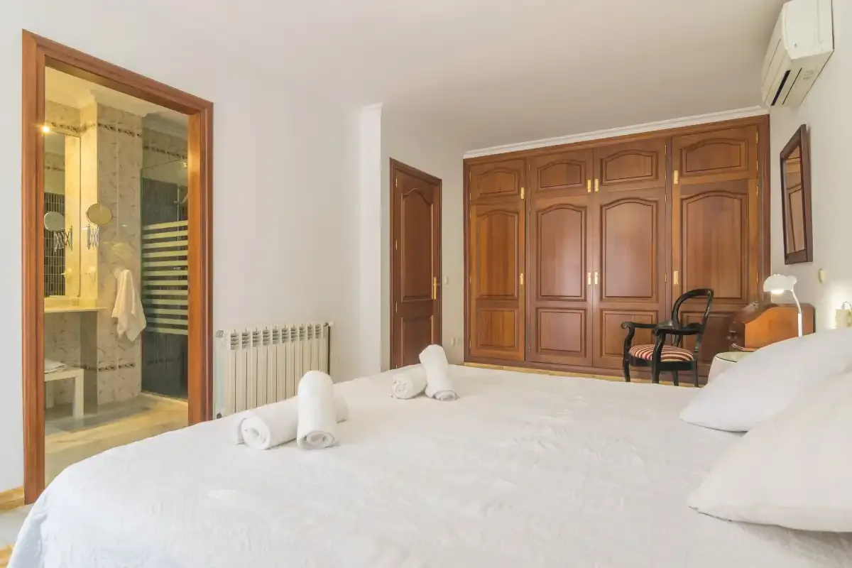 Un dormitorio con una cama grande, un armario de madera y una entrada al baño.