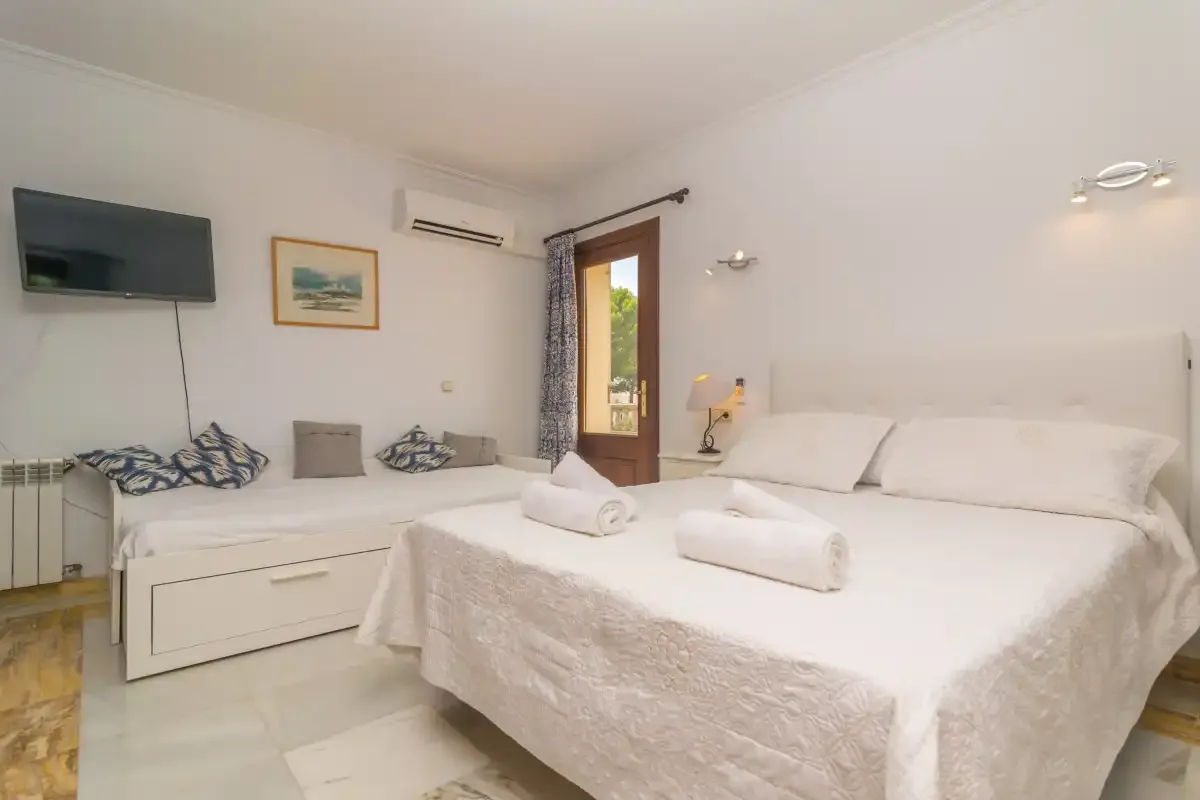 Un dormitorio luminoso con una cama grande y otra más pequeña al lado.