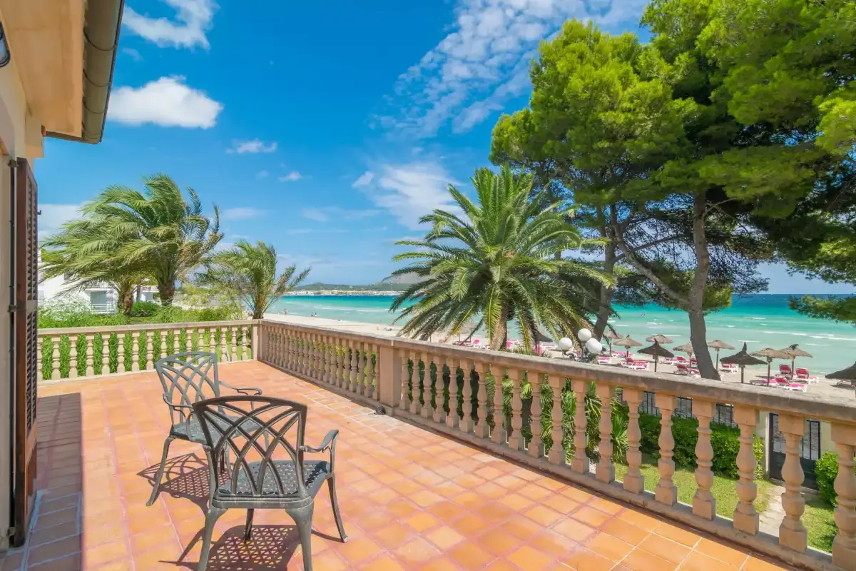 Una terraza embaldosada da a palmeras y al mar.