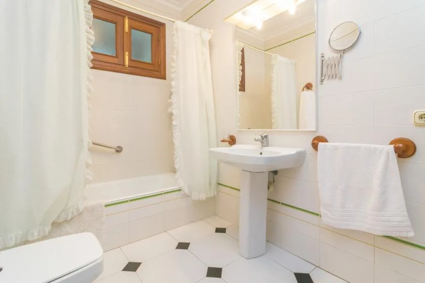 Un baño luminoso con lavabo de pedestal, bañera y espejo.