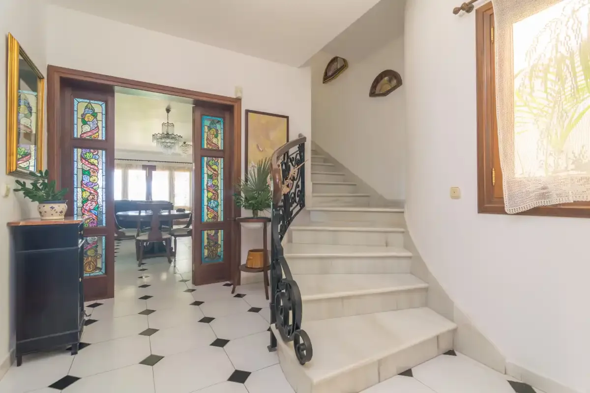 Un pasillo interior con una escalera y un comedor visible a través de una puerta.