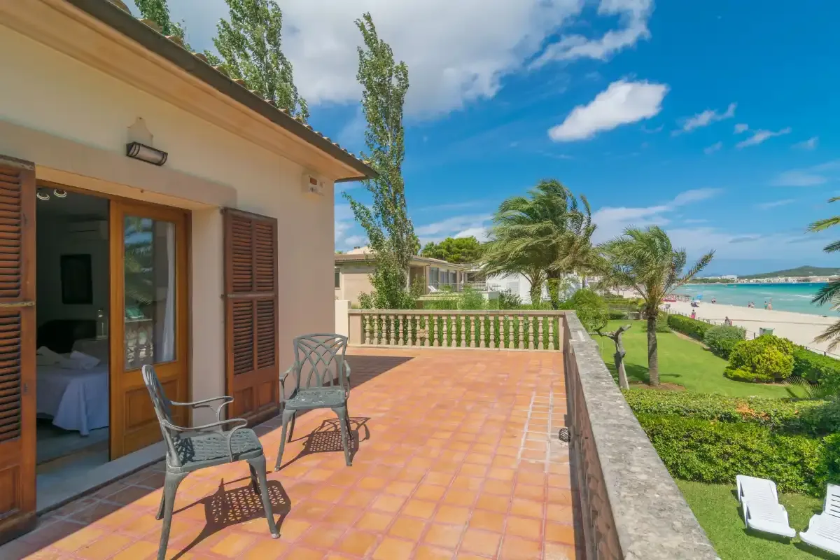 Un patio embaldosado con asientos da a un jardín ajardinado y a la playa.