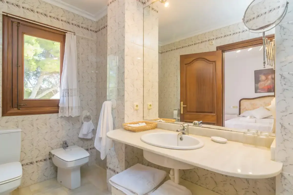 Un baño con azulejos de mármol, un lavabo amplio y una ventana.