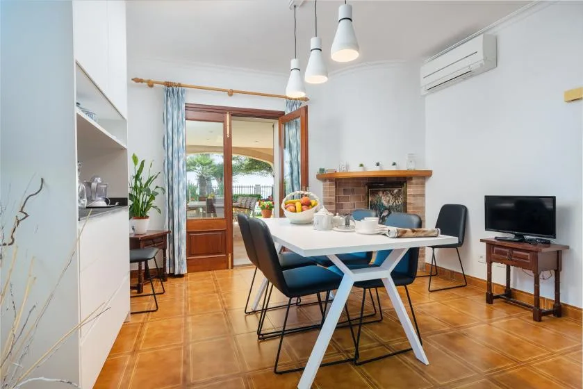 Comedor con una mesa y sillas junto a una puerta abierta al balcón.