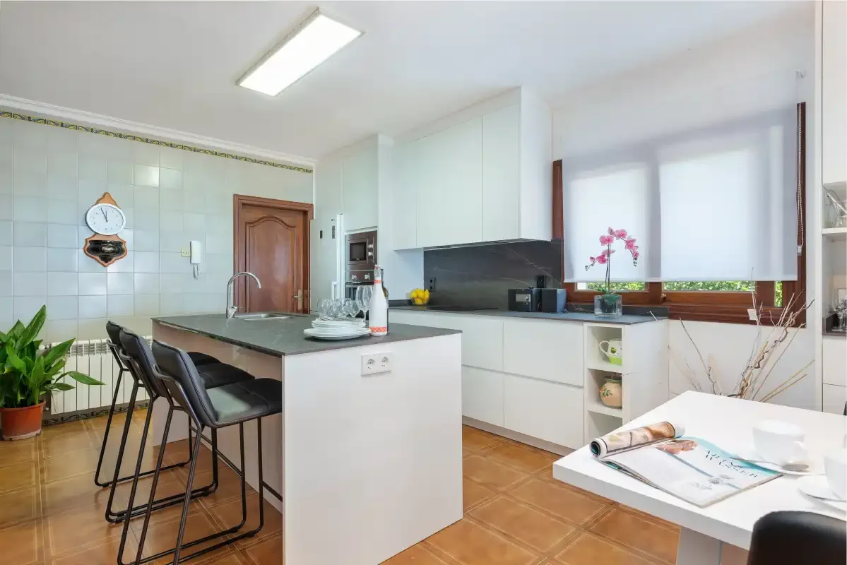 Una cocina luminosa con isla, asientos de comedor y una ventana amplia.