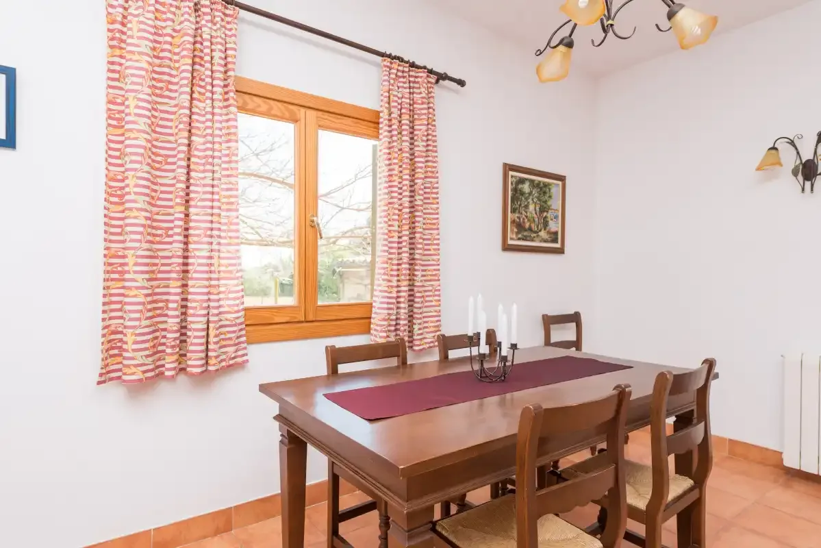 A dining room with a wooden table and chairs beside a curtained window.