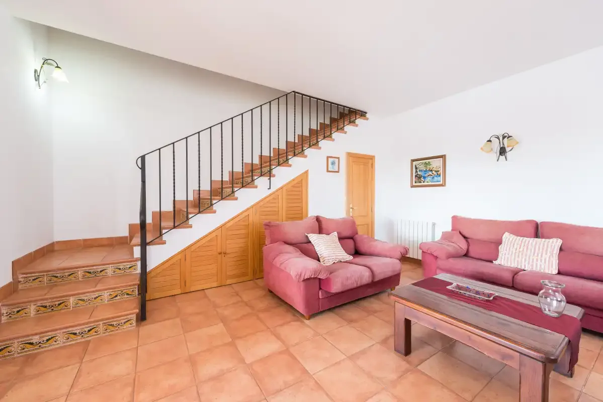A living room with pink seating beside a staircase.
