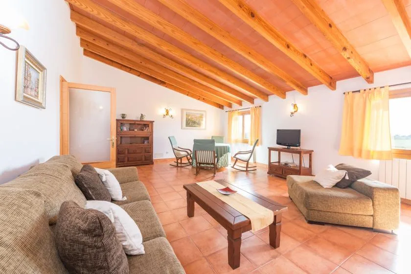 A living room with seating, a coffee table, and exposed wooden ceiling beams.