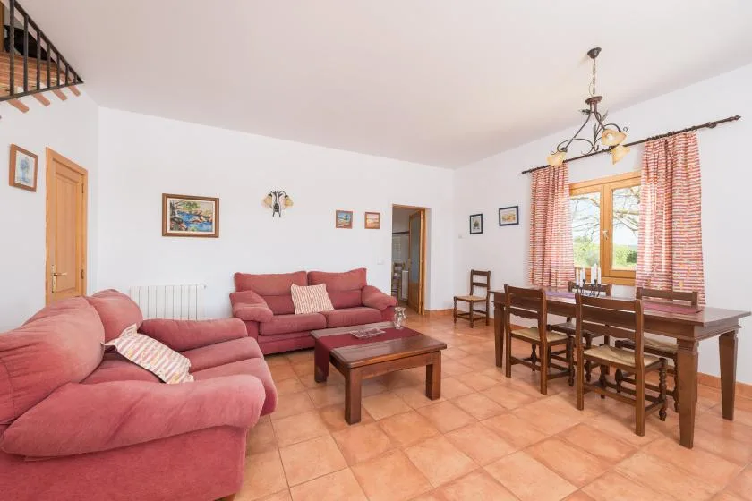 A living and dining room with pink seating and a wooden dining table.