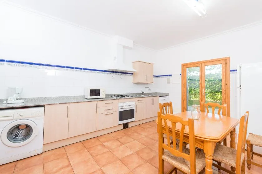 A bright kitchen with a dining table and large glass doors opening to greenery.