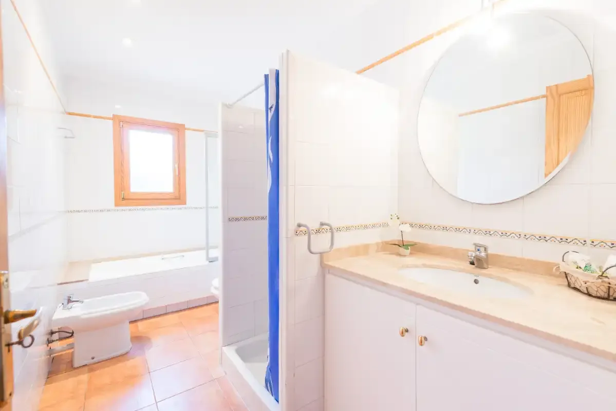 A bright bathroom with a sink, mirror, and shower.