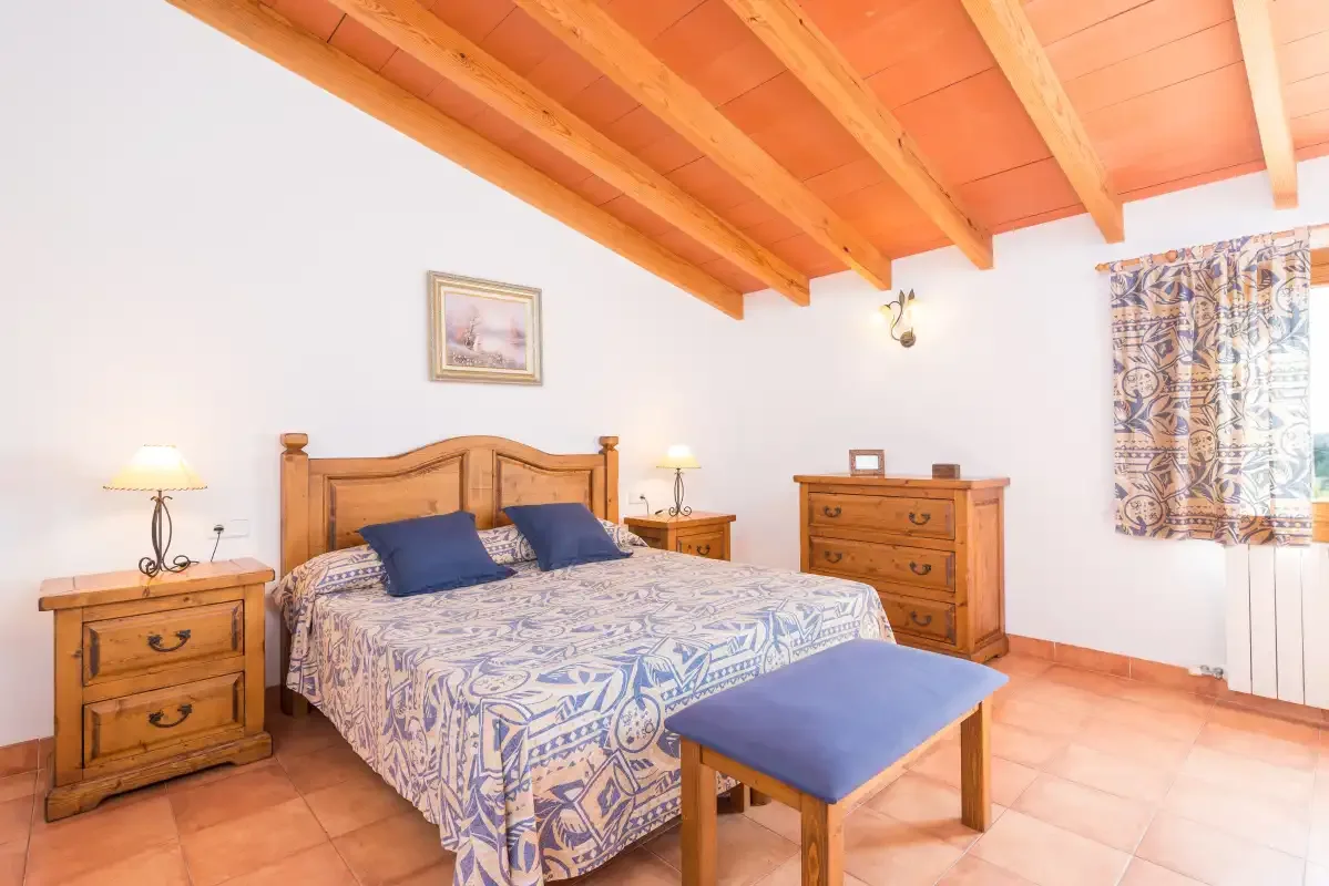 A bedroom with a wooden bed, patterned bedding, and a matching dresser.