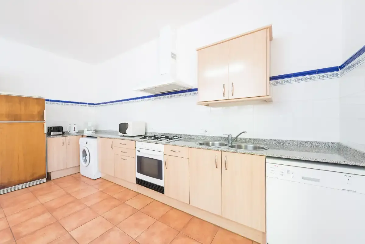 A bright kitchen with light wood cabinets, a countertop, and tiled flooring.