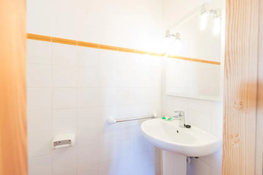 A tiled bathroom with a sink and wall mirror.