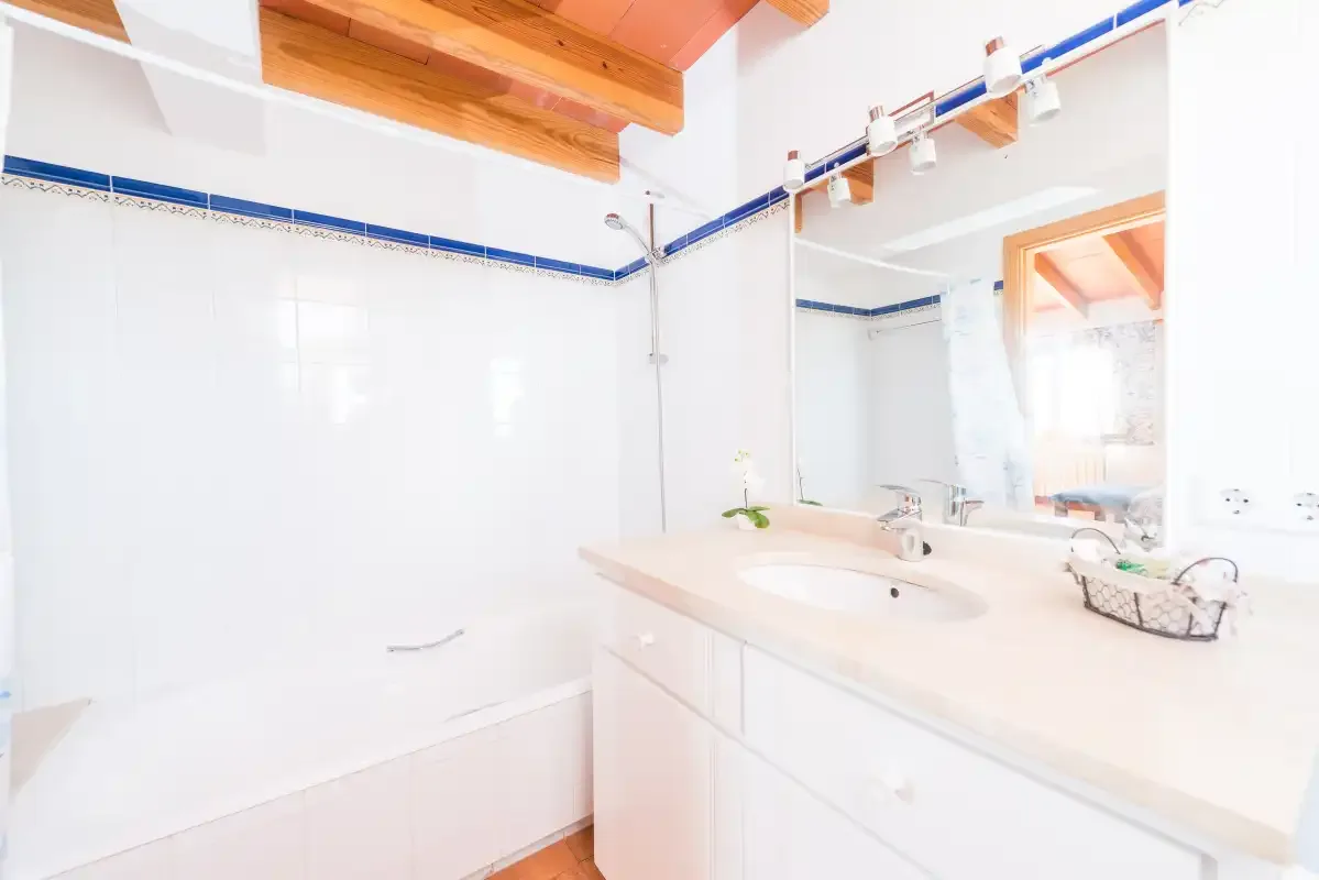 A bright bathroom with a bathtub and sink beneath a large mirror.