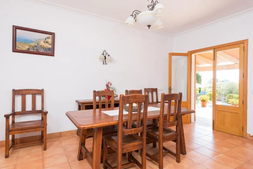 A dining room with a wooden table and chairs beside open doors.