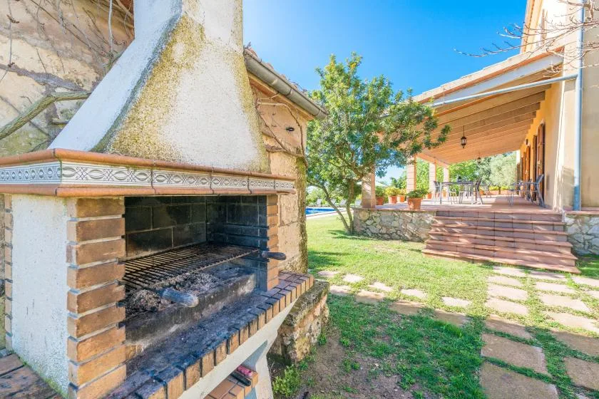 An outdoor patio with a brick barbecue beside a lawn and covered seating area.