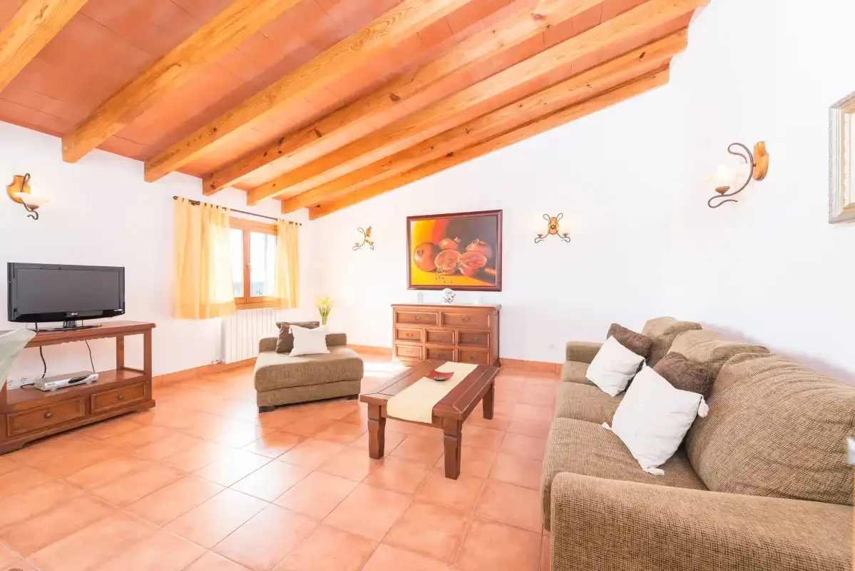 A living room with cushioned seating, a television, and a wooden coffee table.
