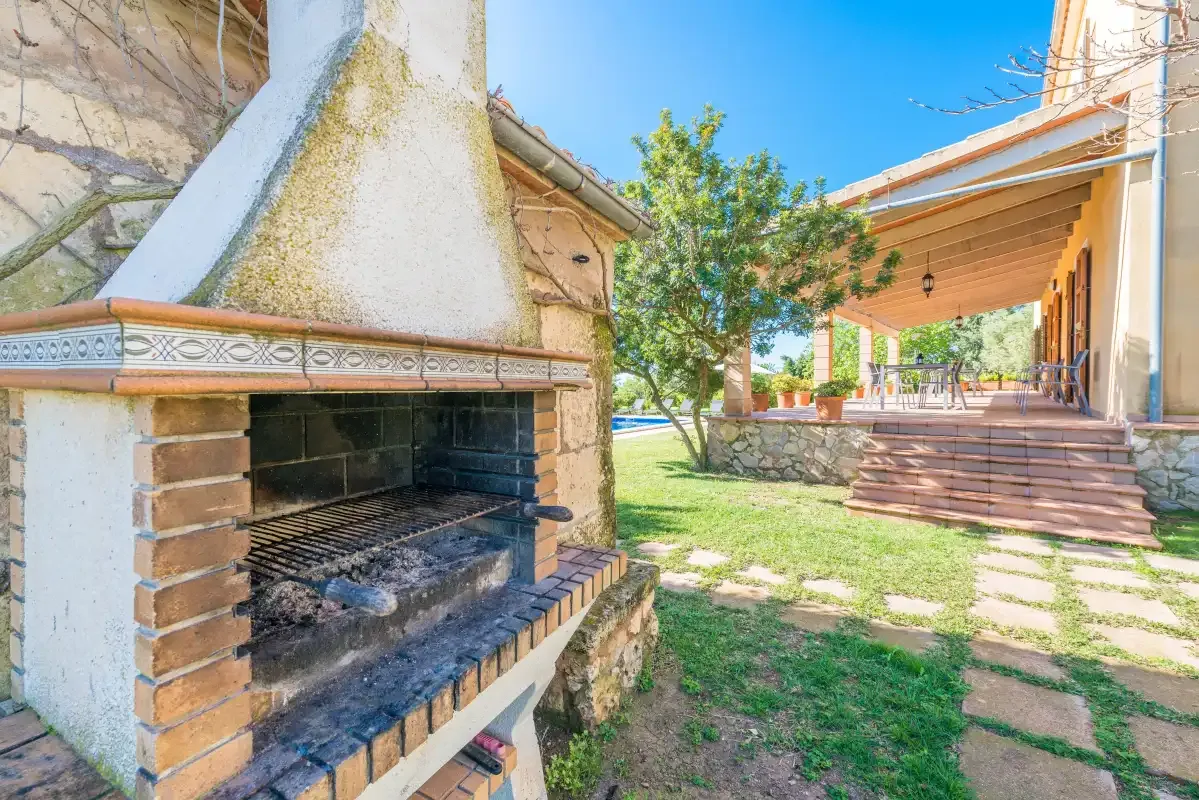 An outdoor patio and garden beside a built-in brick barbecue.