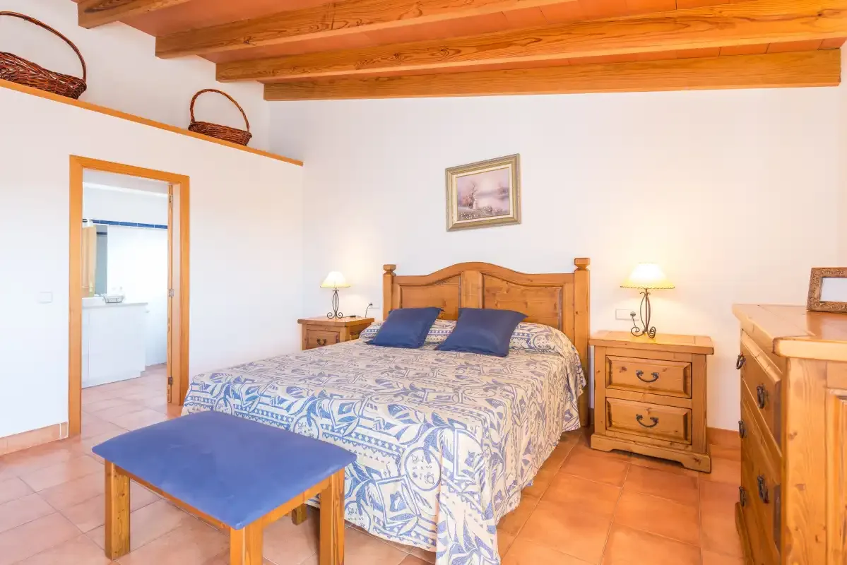 A bedroom with a wooden bed, patterned bedding, and matching wooden furniture.