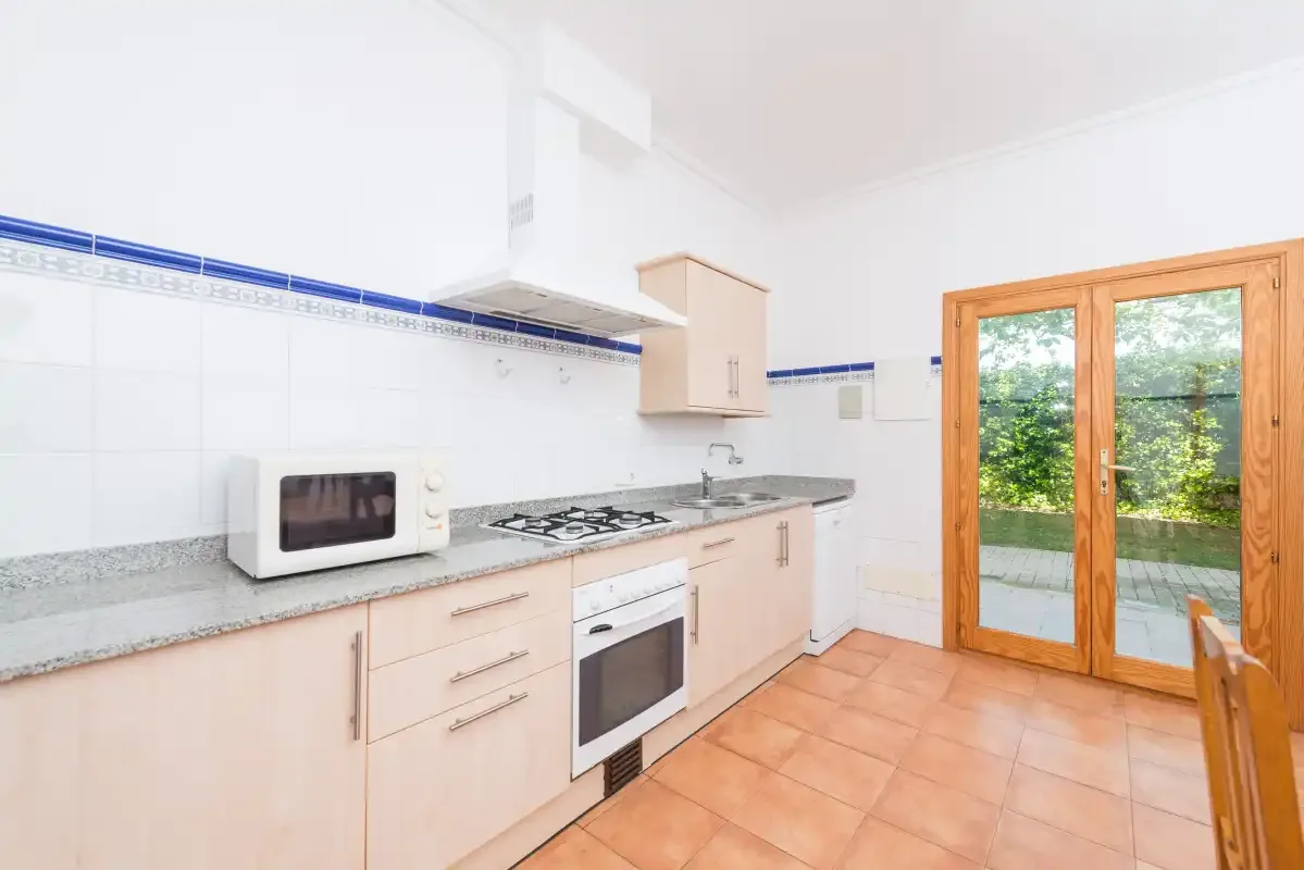 A bright kitchen with countertop appliances and glass doors opening to a garden.