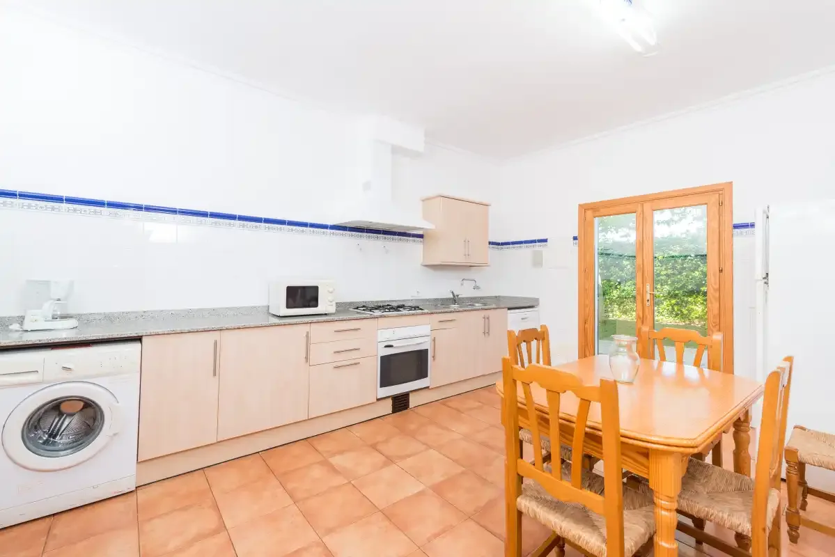 A bright kitchen with a dining table and wooden chairs.