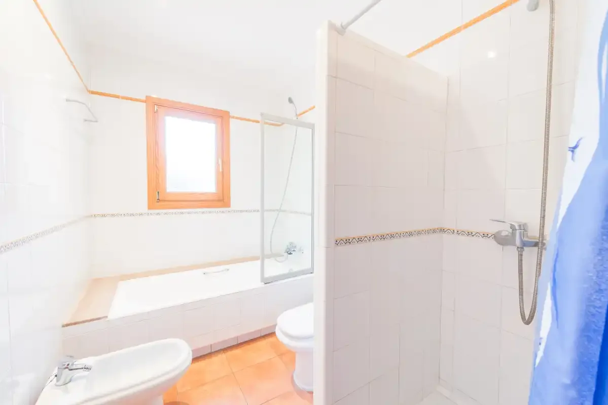 A tiled bathroom with a bathtub, shower, and window.