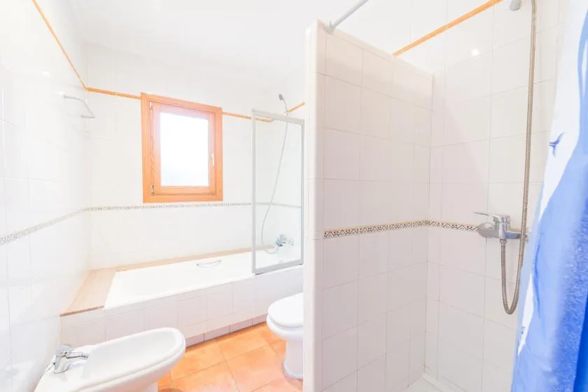 A tiled bathroom with a bathtub, shower, and small window.