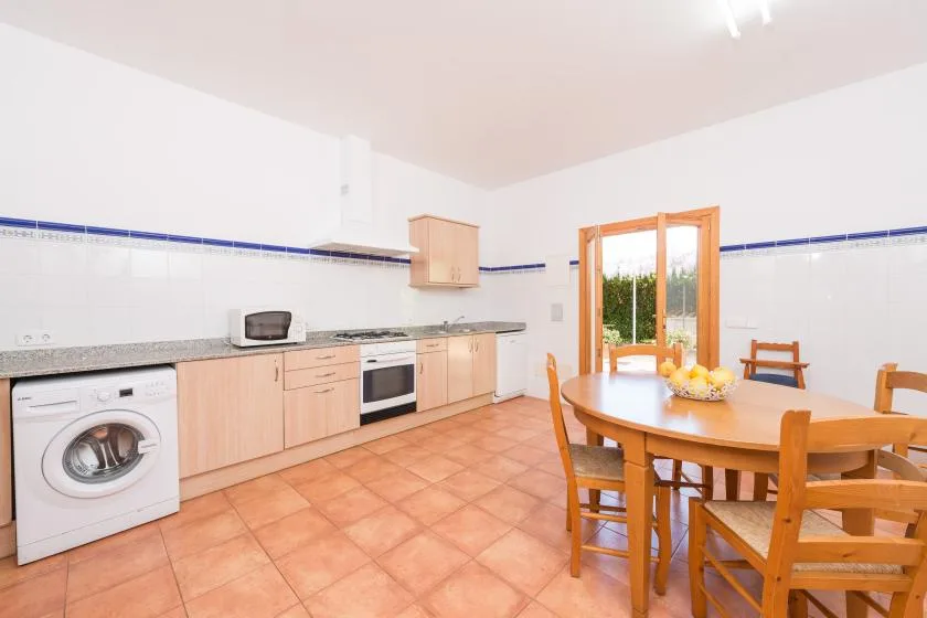A bright kitchen and dining area with wooden cabinetry and a round table.