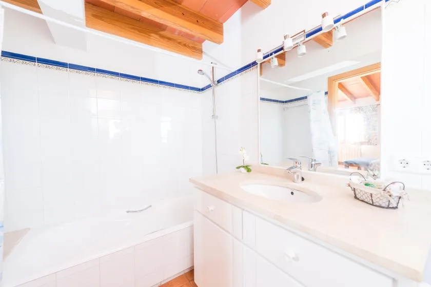 A bright bathroom with a bathtub and a wide sink counter.