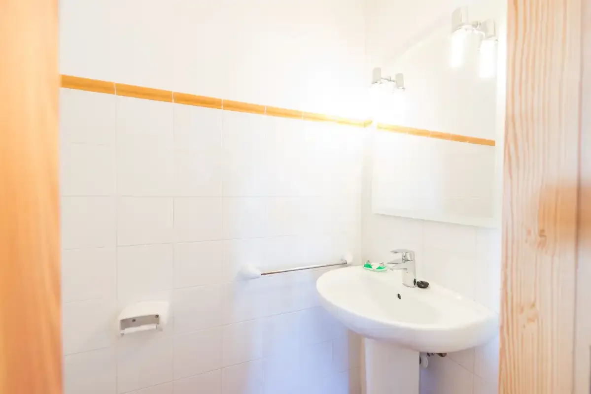 A tiled bathroom with a wall mirror and a white sink.