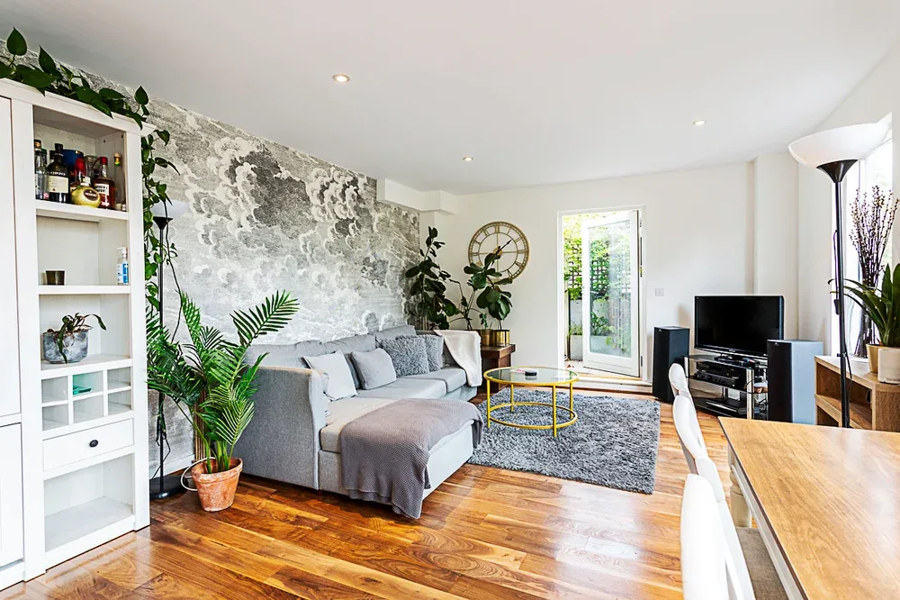 A bright living room with gray seating, a rug, and a television.