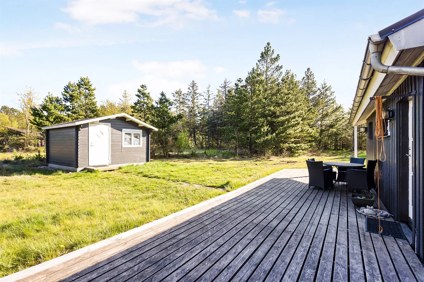 A wooden deck beside a grassy yard and a small outbuilding.